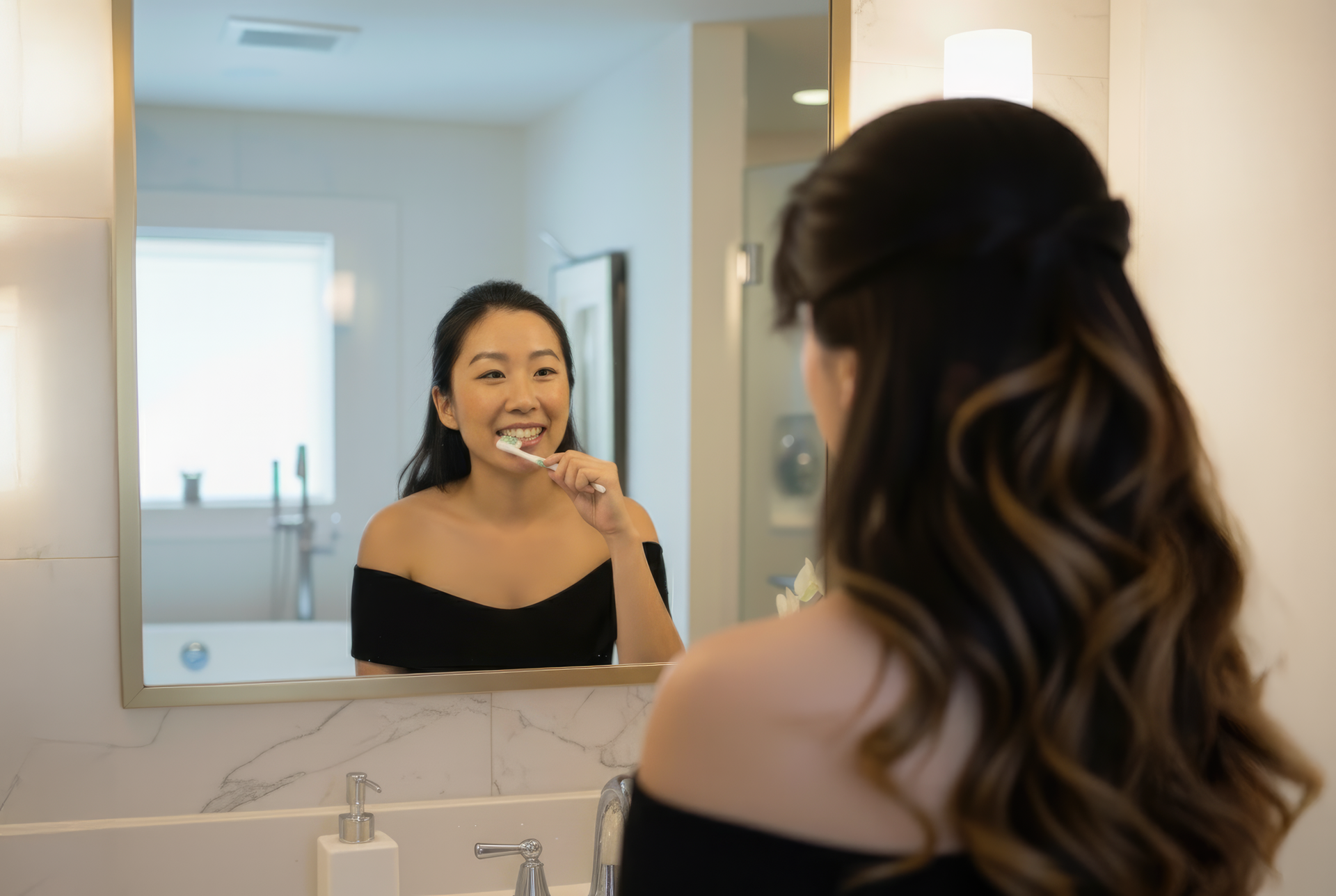 Woman brushing her teeth in front of a bathroom mirror